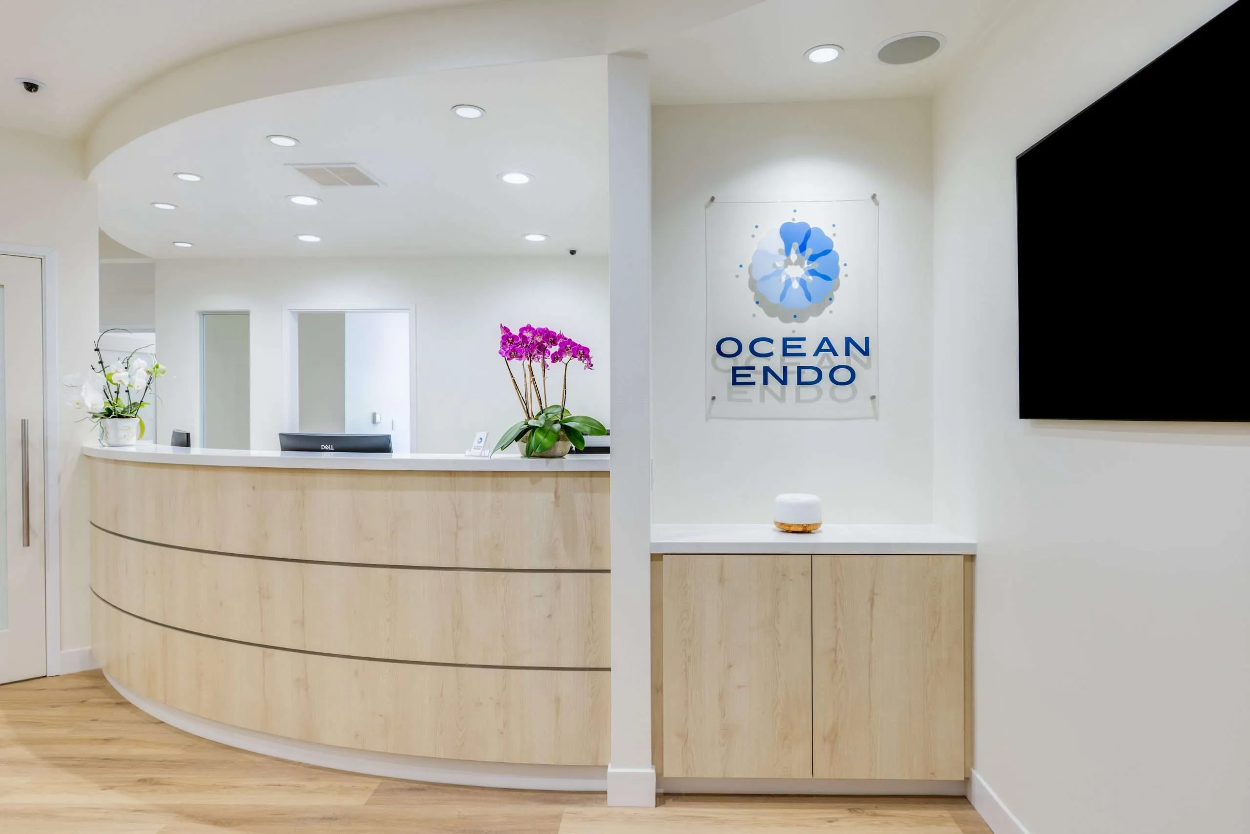 The Ocean Endodontics front desk with the practice logo and fresh orchids